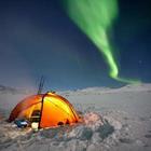 Une tente dans la neige avec une lumière verte dans le ciel